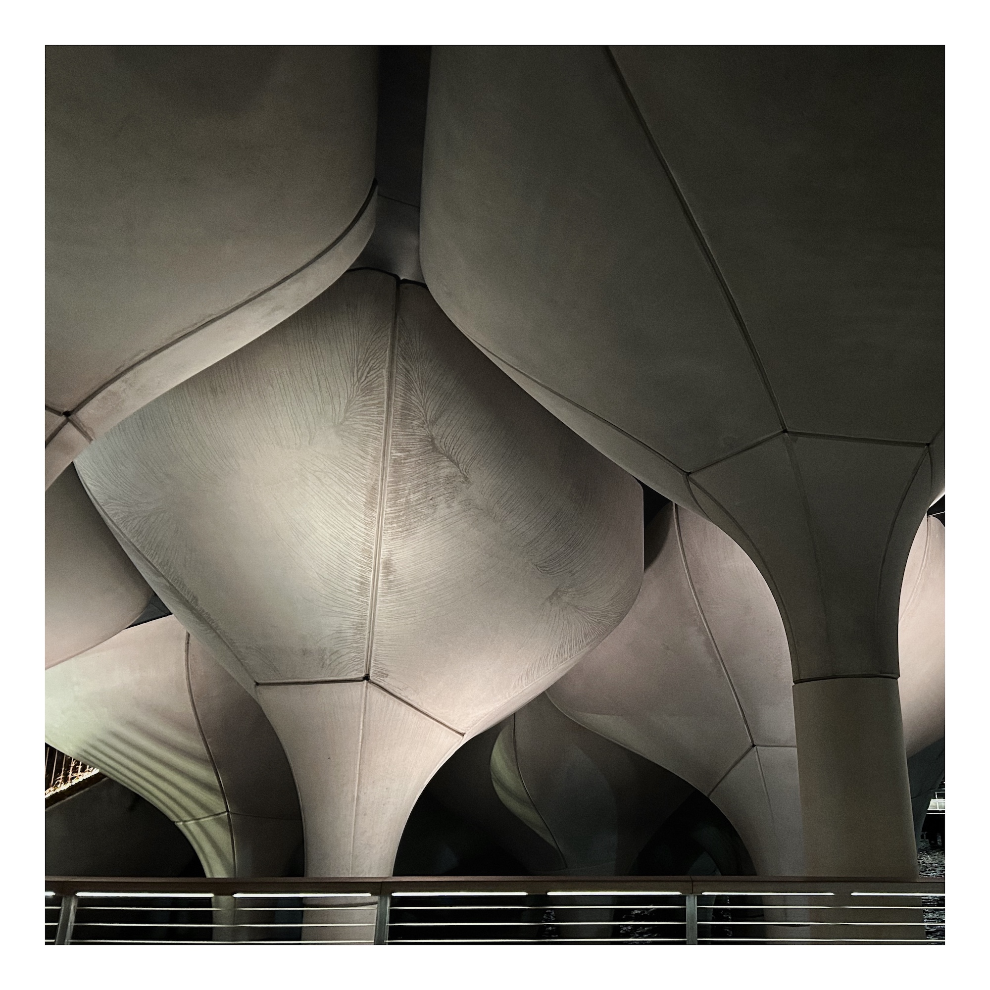 grey mushroom-shaped architectural supports are lit from beneath