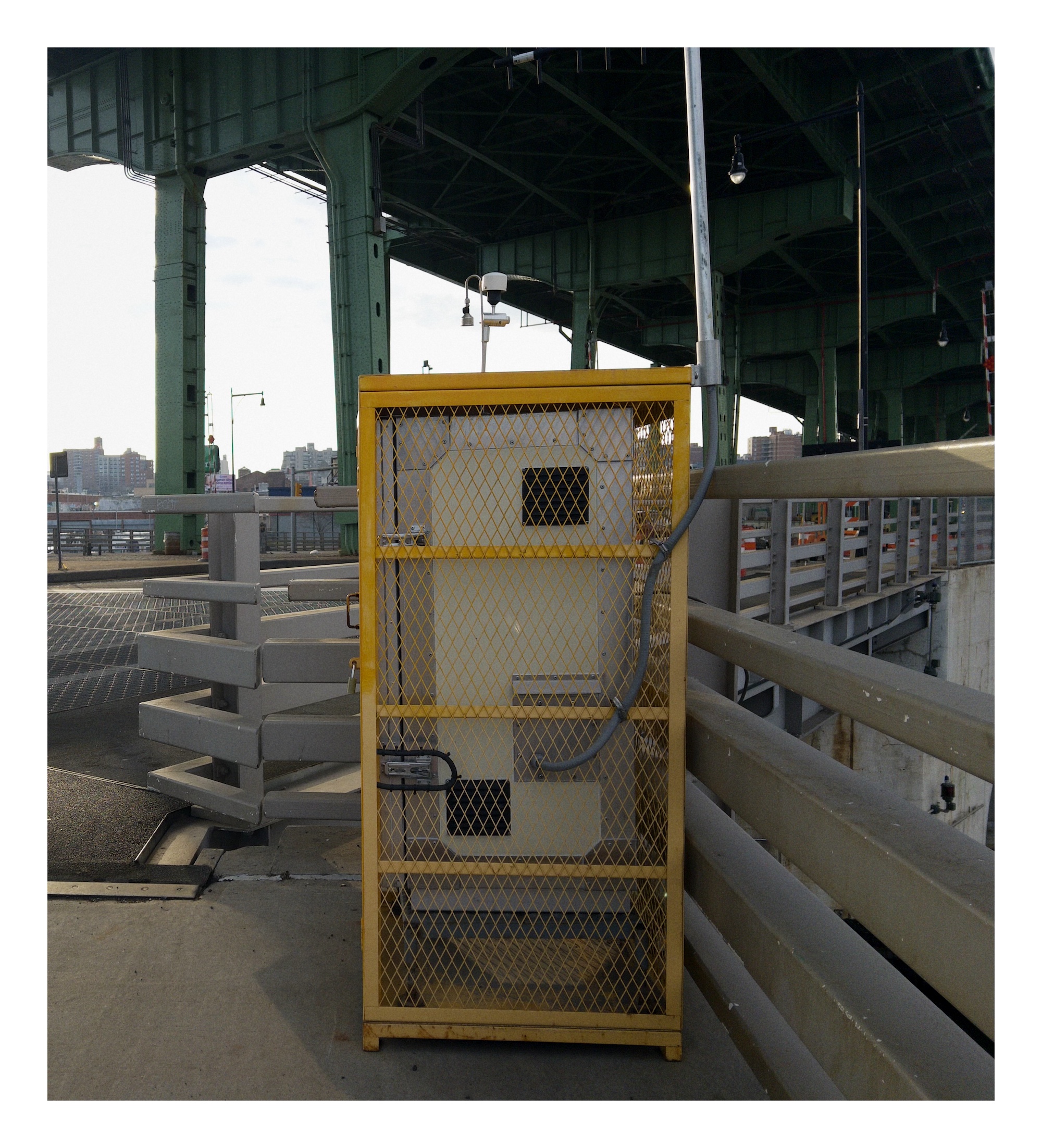 a yellow cage holds electrical equipment on a bridge