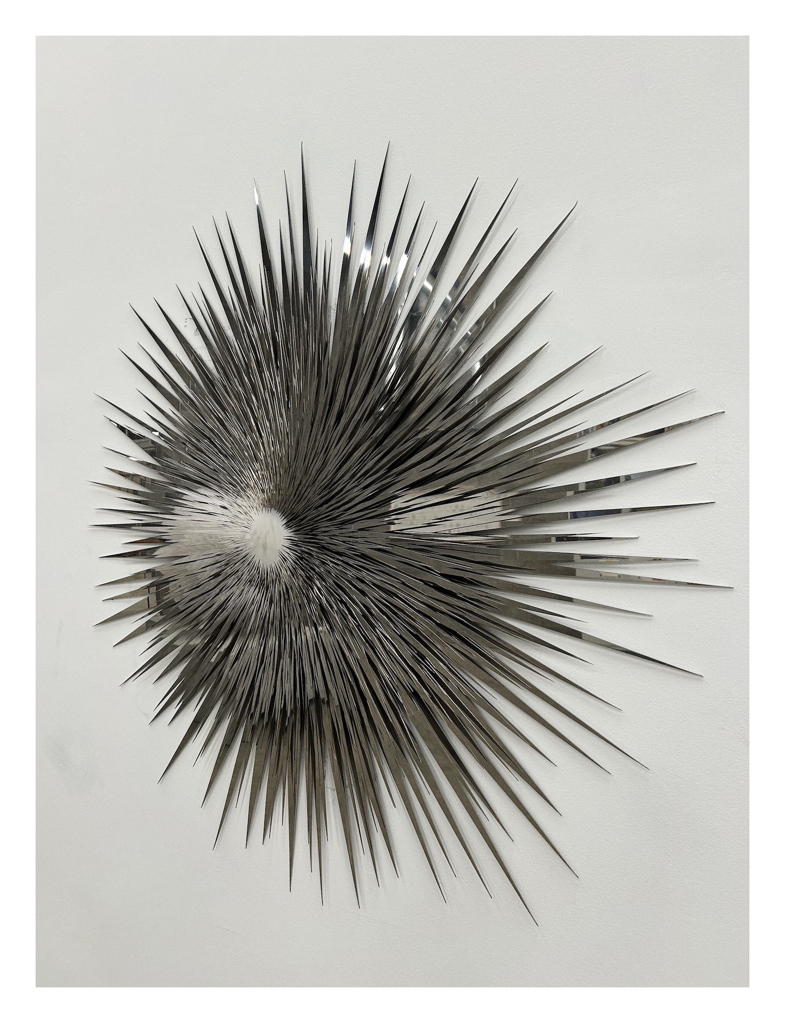 wall-mounted sculpture made of layers of mirrors in a radiant spiky shapes