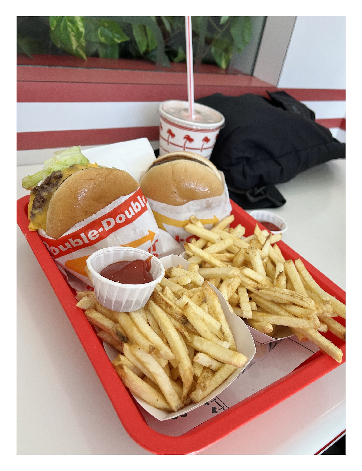 photograph of two hamburgers and two baskets of french fries on a bright red tray