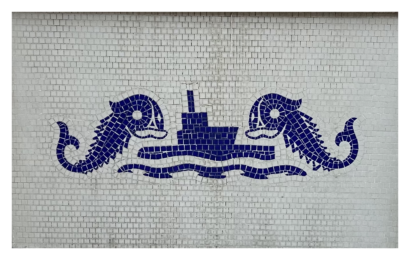 tile mosaic in white and blue depicting two sea monsters on either side of a ship